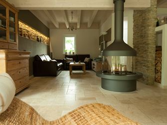 Un salon avec une chéminée sur un sol en travertin Light, au premier plan, un fauteuil